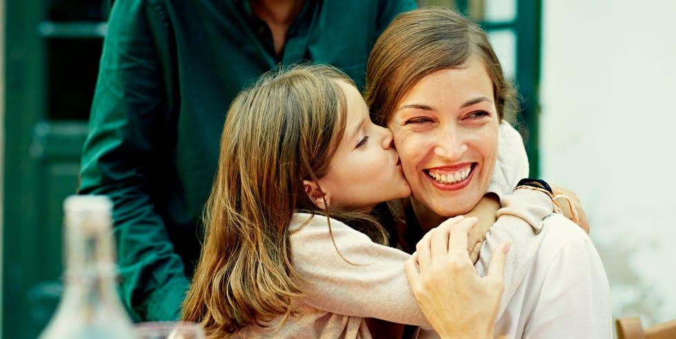 Girl kissing mother while celebrating cute girl kissing mother on cheek while celebrating at outdoor table in yard