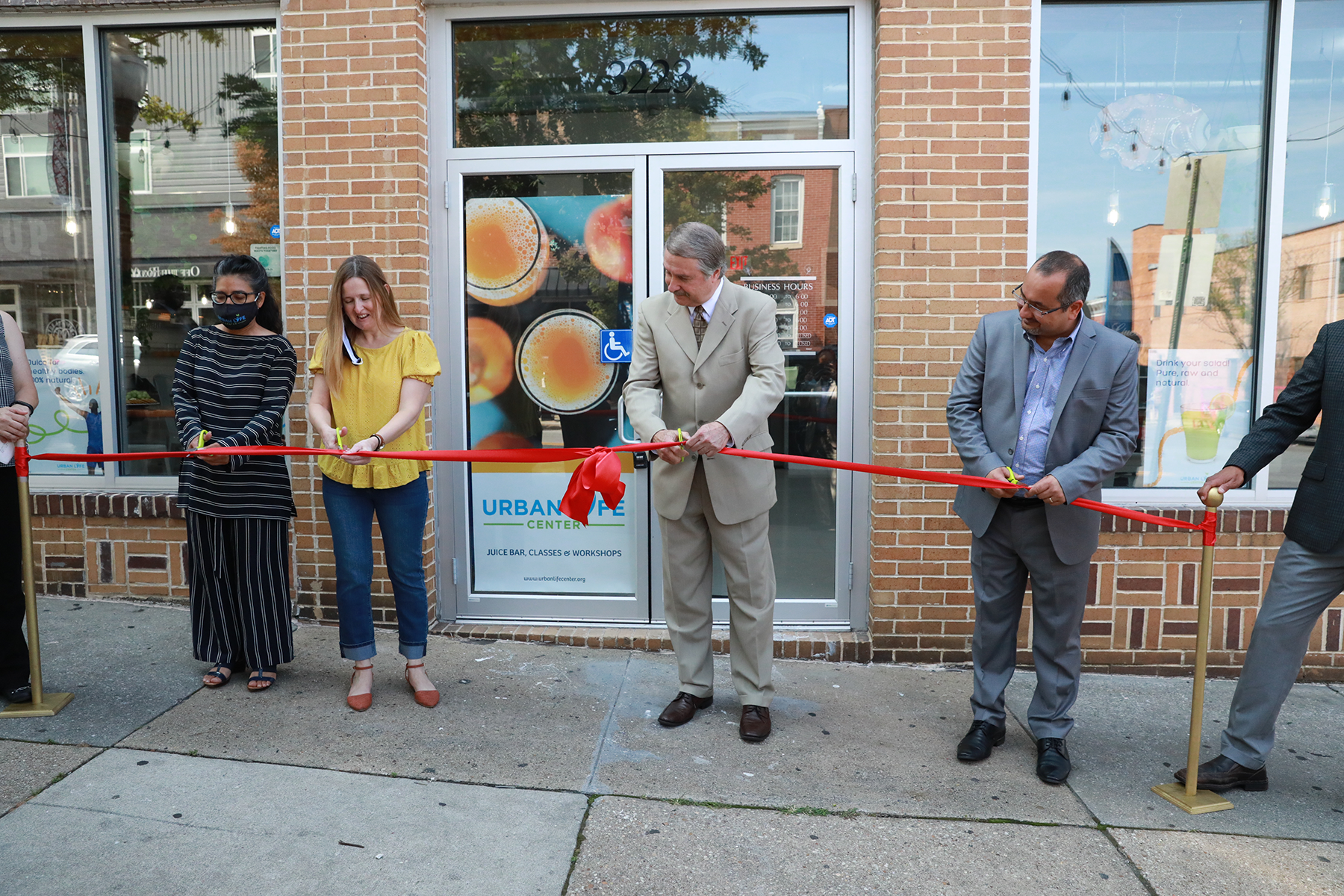 Several people cut a ribbon at a building dedication